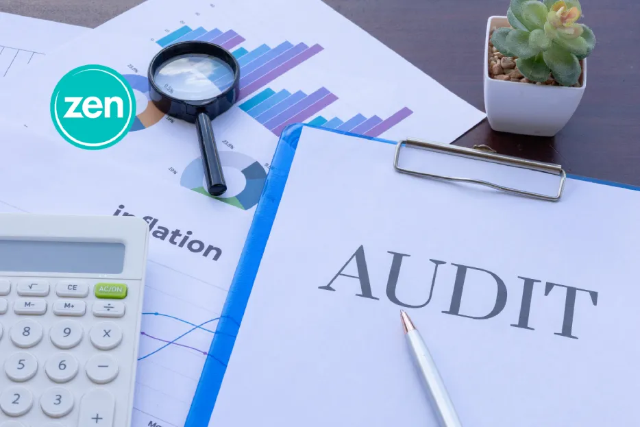 Audit document, calculator, magnifying glass, and financial charts on a desk for review.