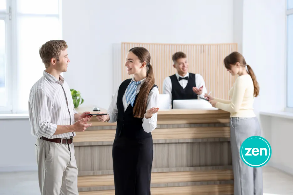 Hotel guest checking in with a female receptionist at a modern reception desk.