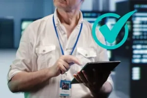 Man in white shirt uses a tablet with a green checkmark indicating approval.