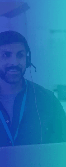 Smiling man with a beard wearing a headset, working at a computer.