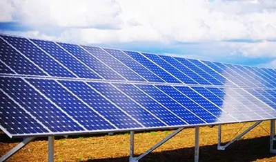 Rows of blue solar panels installed in a field under a partly cloudy sky.