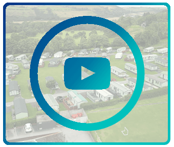 Play button icon overlaid on a blurred aerial view of a caravan park.