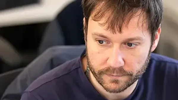 Bearded man with brown hair looking down intently, concentrating on a task.