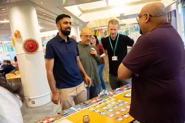 A diverse group of people interact around a colorful table display at an event.