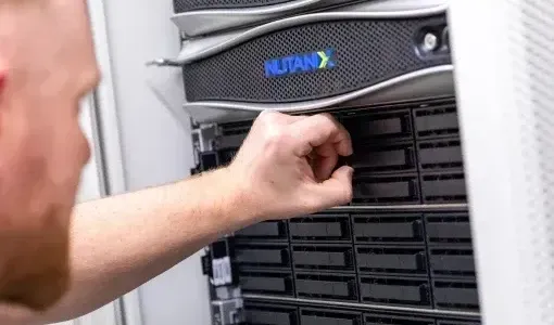 Technician inserts a drive into a Nutanix server rack.